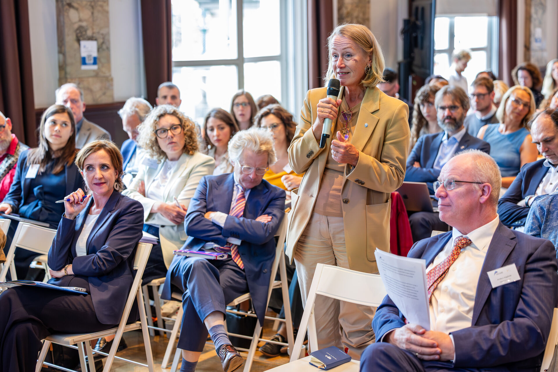 Woman holding a microphone, asking a question to the speakers.